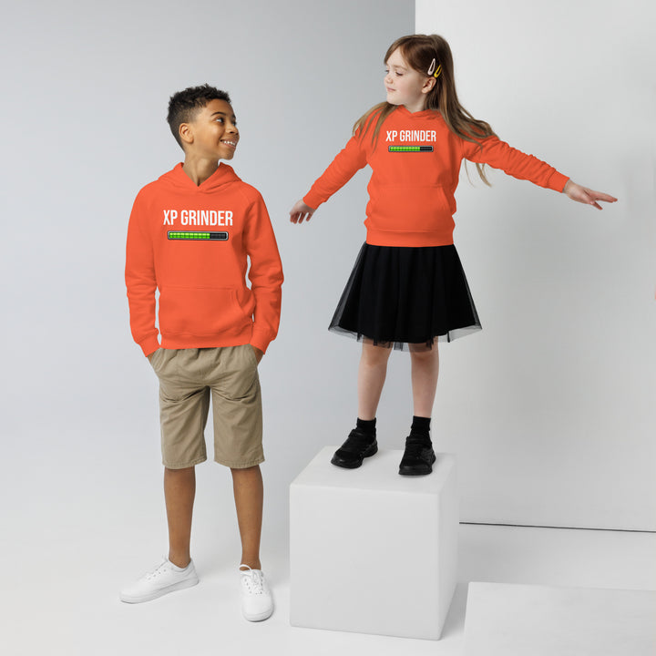 Two kids wearing XP Grinder eco-friendly kids hoodie, a boy in shorts and a girl in a skirt, standing on a cube.