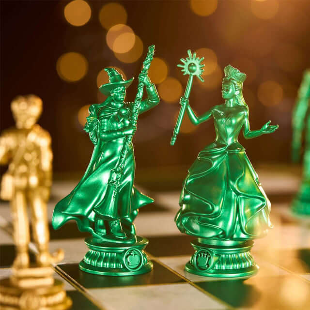 Wicked Chess Set figures, green Queen and King pieces, standing on a chessboard with a bokeh background.