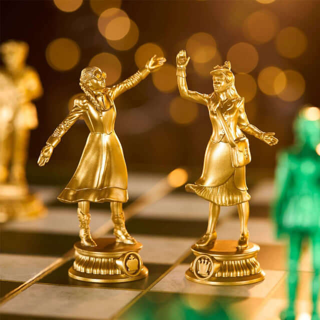 Wicked Chess Set featuring golden figurines of Glinda and Elphaba on a chessboard.